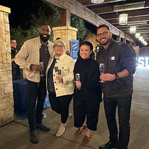 four people pose for camera